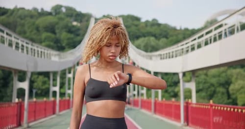 Sporty African American Woman Looking at Her Sport Bracelet on Hand Checking Data on Fitness Tracker