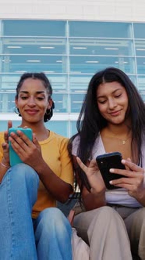Young Women Friends Use Phones Together