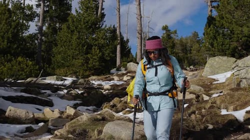 Hiker Walking in Snowy Mountain Forest Trail with Backpack and Trekking Poles