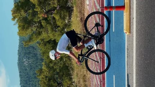 Radfahrer mit weißem Helm fährt Fahrrad auf dem Radweg. Vertikales Video