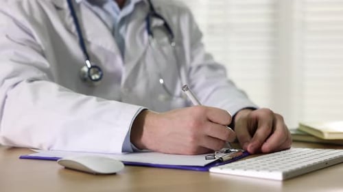 Doctor Writing Notes at Desk in Office Setting