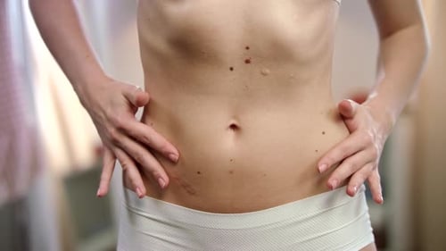 Une jeune femme sensuelle touche sa taille, révélant sa silhouette mince parfaite