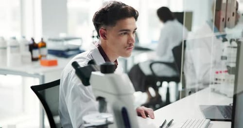 Young Adult Lab Worker Typing and Taking Notes