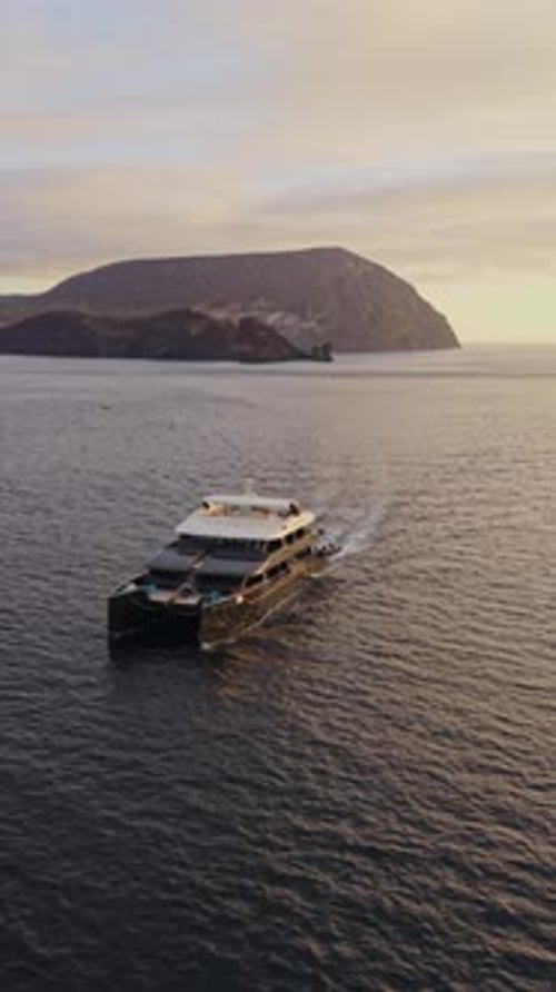 Yacht de luxe naviguant dans les eaux calmes du Pacifique, côte volcanique des Galapagos, brillant sous un coucher de soleil doré