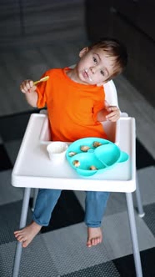 Child Eating Food in High Chair
