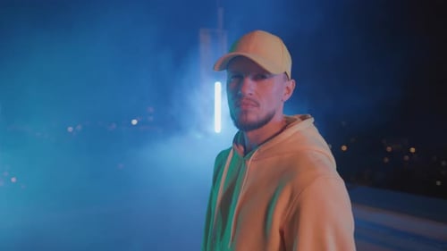 Positiver, gutaussehender, charismatischer junger Tänzer, Hip-Hop-Straßenkünstler, gestikuliert nachts vor der Kamera