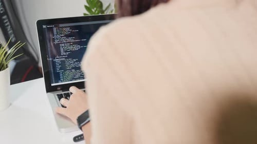 Programmiererin, die Programm-HTML-Code schreibt, sitzt am Arbeitsplatz im Büro