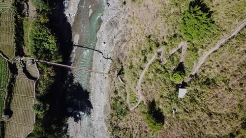 mountainous zig zag dirt gravel trail leading to metal suspension bridge river crossing emerald moun