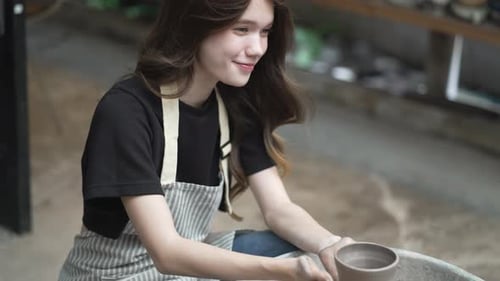 Young women is making earthenware at workshop.