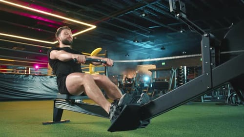 Muscular Man Uses Rowing Machine at Urban Gym