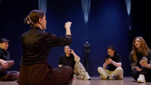 Ensayo de teatro contemporáneo con un conjunto de jóvenes artistas sentados en el escenario como algo expresivo