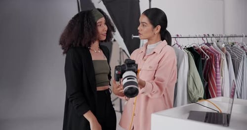 Stylish Women Discussing Digital Camera in Fashion Studio