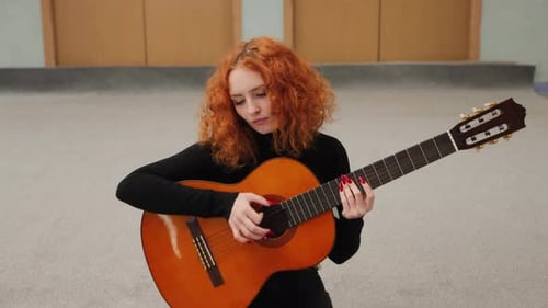 Woman Plays Acoustic Guitar in Indoor Room