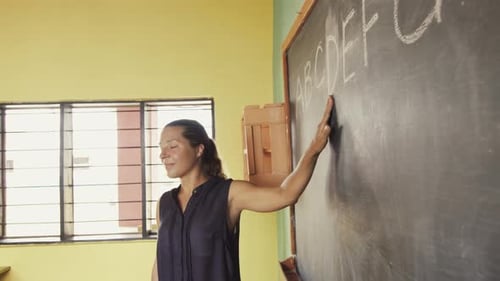 Enthusiastic Woman Writes Alphabet on Blackboard in Classroom