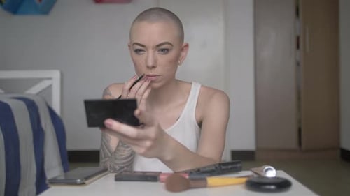 Woman Applies Makeup in Bedroom Holding Mirror