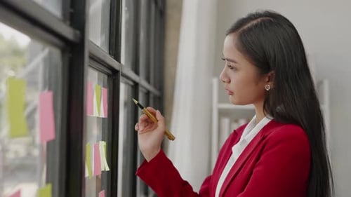 Empresaria: escriba su estrategia empresarial en notas y péguelas en la pizarra para la planificación empresarial y el marketing.