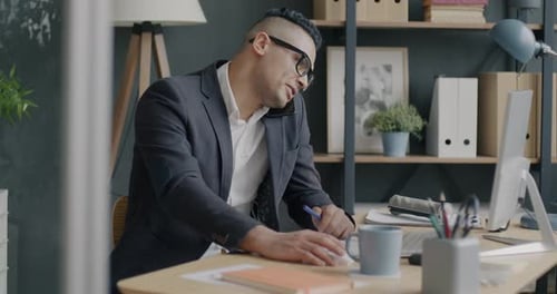 Portrait of Businessman Talking on Mobile Phone and Writing Busy with Conversation in Office