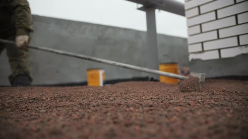 Worker Smoothing Stones on an Urban Rooftop