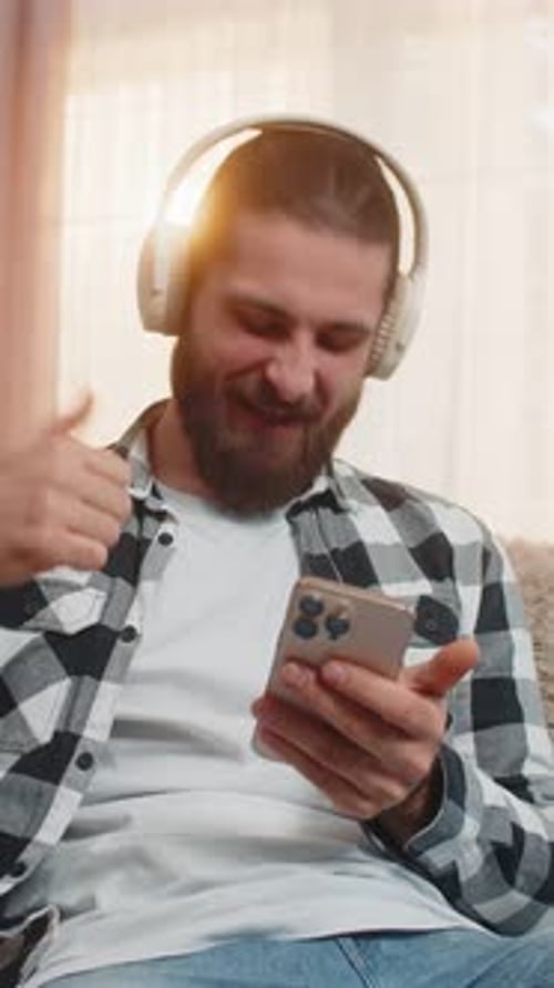 Bearded Man Enjoys Music with Headphones and Phone