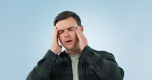 Stress, headache and man in studio with anxiety, vertigo or mental health crisis on blue background