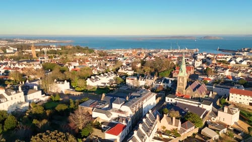 High circling drone footage of the roof tops of St Peter Port Guernsey in the golden hour with views