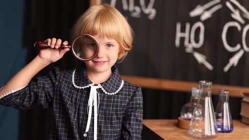 Child Looks Through Magnifying Glass in Classroom