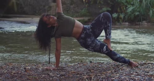 A girl doing yoga next to a flowing river on a bright Caribbean day.