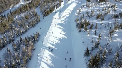 Aerial of Snowy Ski Slope with People Skiing and Chairlifts in Mountain Resort