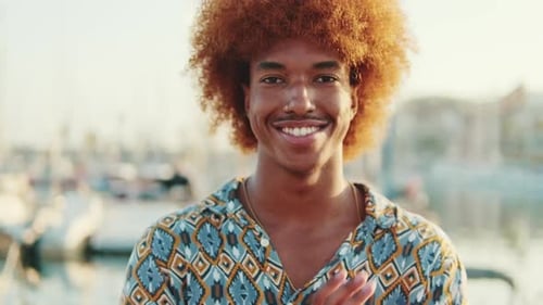 Funny guy smiling and laughing against blured background of the sea and yachts