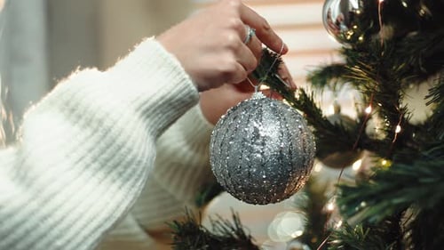 Woman Decorating Christmas Tree with Silver Ornament