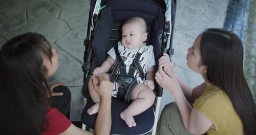 Two Adults Admiring Cute Infant in Stroller