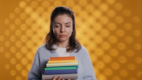Portrait of Upbeat Woman Holding Pile of Books Studio Background