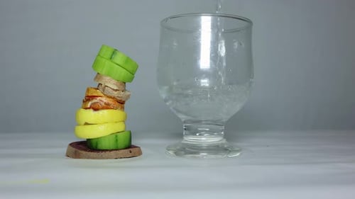 glass of water with Stacked Slices of Fresh Turmeric, Beetroot, Lemon, Cucumber, and Ginger