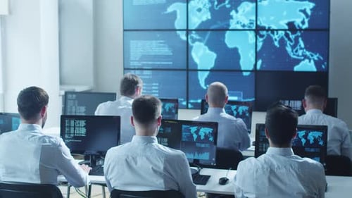 Un profesional de seguridad informática del equipo trabaja en una luminosa sala de monitoreo llena de pantallas