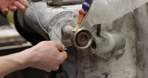 Worker grinding piece of glass in workshop, closeup