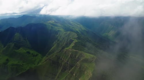 Ätherische Wolken schweben über den grünen Bergtälern Luftbild der bewölkten Bergtäler