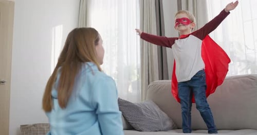 Boy in Superhero Costume Posing with Adult in Home
