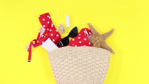 Bolsa con accesorios de playa sobre fondo amarillo, capa plana