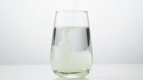 Powder Being Mixed Into Water in Glass