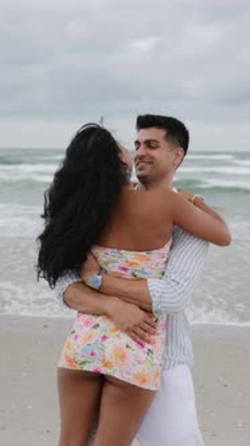 Romantic Couple Embracing and Kissing on a Windy Beach