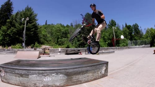 BMX rider manual to bar spin on a ledge