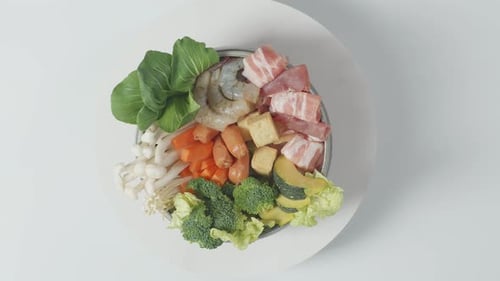 Una olla de ingredientes de shabu dando vueltas sobre una mesa blanca en la cocina