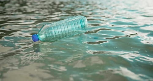 Water pollution, trash and plastic bottle litter at beach for poor waste management