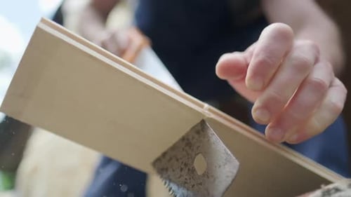 Man cuts wooden plank with hand saw