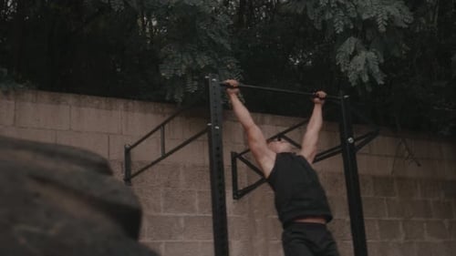 Muscular Man Doing Pull-Ups Outdoors