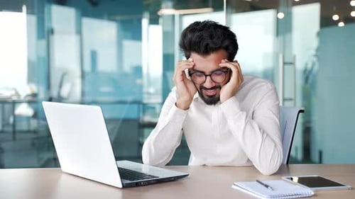 Young businessman has depression suffering from mental pain sitting at workplace in modern office.