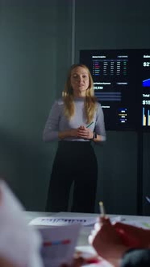 Woman Presents Charts to Colleagues in Meeting Room