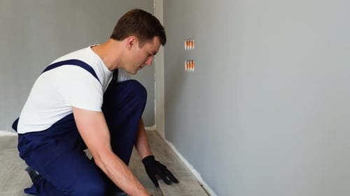 Man Installing Wooden Floorboards Indoors