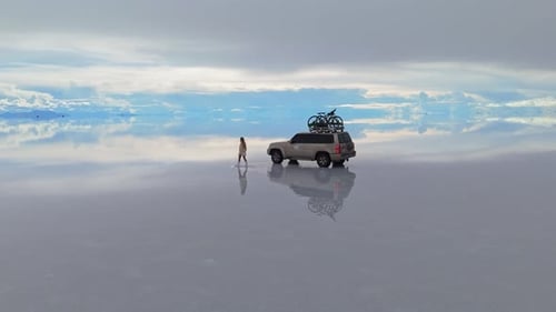 Una mujer camina por la superficie reflectante del Salar de Uyuni de Bolivia capturando la serena belleza