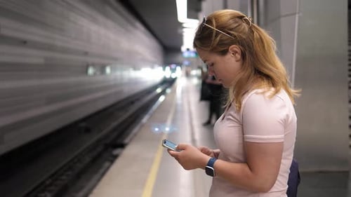 Woman Using Phone at Subway Station Waiting for Train